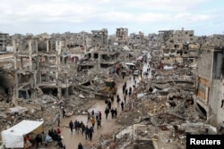 Palestinians walk past the rubble of buildings destroyed during the Israeli offensive, on a rainy day in Gaza City amid a ceasefire between Israel and Hamas, Feb. 6, 2025.