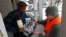 Louis Singleton receives water filters, bottled water and a test kit from Michigan National Guard Specialist Joe Weaver as clean water supplies are distributed to residents, Jan. 21, 2016 in Flint, Mich.