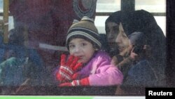 Un niño y su familia parten de Alepo, Siria, al comenzar la evacuación de civiles.