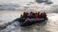 FILE - Migrants board a smuggler's boat in an attempt to cross the English Channel near Dunkirk, France, April 26, 2024. Several people, including a child, died trying to cross the English Channel from France to England, French Interior Minister Bruno Retailleau said Saturday. 