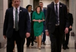 Flanked by her security detail and aides, Speaker of the House Nancy Pelosi, D-Calif., arrives to update reporters as lawmakers continue work on a coronavirus aid package, on Capitol Hill in Washington, March 12, 2020.