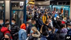 People wear face masks but stand close together as they wait for a subway train in Frankfurt, Germany, Dec. 2, 2020.