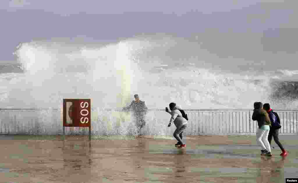 Tourists take a picture with sea waves during the storm &quot;Gloria&quot; on Barceloneta beach in Barcelona, Spain.