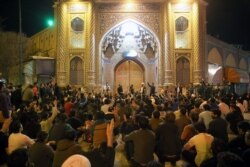 People gather outside the closed doors of the Fatima Masumeh shrine in Iran's holy city of Qom on March 16 2020. Iran closed four key Shi'ite pilgrimage sites across the Islamic republic on March 16.