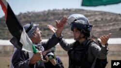 FILE - A Palestinian protester argues with Israeli security forces to prevent shooting tear gas at Palestinian protesters during a demonstration against Israeli settlements in the village of Qaryout, near the West Bank city of Nablus, September 15, 2023.