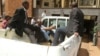 FILE: Zimbabwean pastor Evan Mawarire reads a bible as he arrives escorted by detectives at the Harare Magistrates court, Zimbabwe, Feb. 3, 2017.
