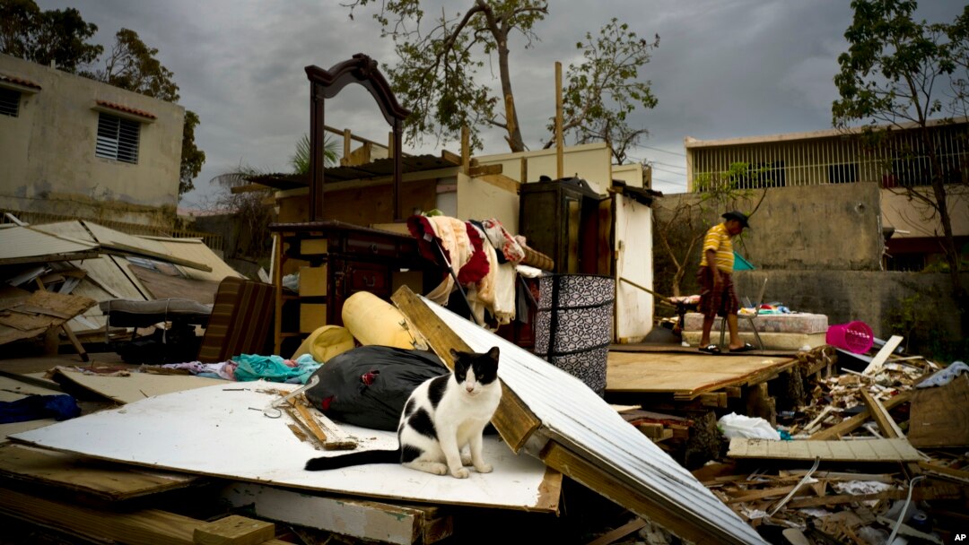 Efrain Diaz Figueroa, right, walks by his sister's home destroyed in the passing of Hurricane Maria, in San Juan, Puerto Rico, Oct. 9, 2017.