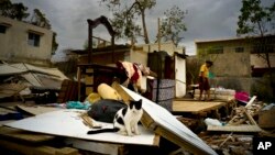 Efrain Diaz Figueroa, right, walks by his sister's home destroyed in the passing of Hurricane Maria, in San Juan, Puerto Rico, Oct. 9, 2017.