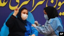 FILE - Sara Goudarzi, a nurse from the Imam Khomeini Hospital, flashes a victory sign as she receives a Russian Sputnik V coronavirus vaccine in a staged event at Imam Khomeini Hospital in Tehran, Iran, Feb. 9, 2021. 