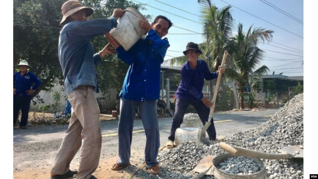 Các lão nông đang tham gia xây cầu. Hình: Trích xuất từ website báo Tuổi Trẻ/Hải Triều.