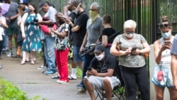 Steven Posey checks his phone as he waits in line to vote, Tuesday, June 9, 2020, at Central Park in Atlanta. Voters reported wait times of three hours. (AP Photo/John Bazemore)