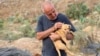 In this photo provided by Mashala Shelter, Hussein Hamza carries a puppy at his animal shelter in Kfour, south Lebanon in 2024. (Mashala Shelter via AP)