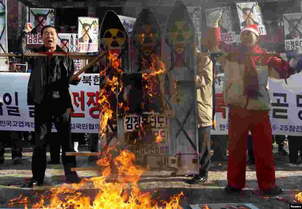 Anti-North Korea protesters burn signs during a rally denouncing North Korea's rocket launch, in central Seoul December 12, 2012. North Korea successfully launched a rocket on Wednesday, boosting the credentials of its new leader and stepping up the threa