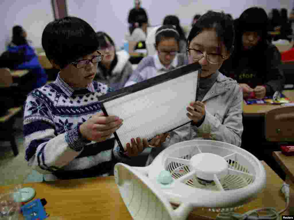 北京一所学院的学生学习如何自制空气清洁器，试图把过滤网放到电扇上（2014年10月23日）