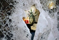 A Statue of Liberty painting is seen through a smashed Dolce and Gabbana store window in the SoHo neighborhood of New York, June 1, 2020.