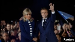 El presidente francés, Emmanuel Macron, saluda en el escenario junto a su esposa, la primera dama francesa Brigitte Macron, tras su reelección en Francia, el 24 de abril de 2022. REUTERS/Benoit Tessier.