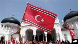 Seorang warga Aceh melambaikan bendera Bulan Sabit-Bintang dalam pawai di luar Masjid Besar Baiturrahman, Banda Aceh awal April lalu (Foto: dok). Juru bicara presiden, Julian Aldrin Pasha mengatakan Presiden SBY akan membatalkan Qanun terkait bendera dan lambang Aceh jika pemerintah setempat tidak melakukan koreksi.