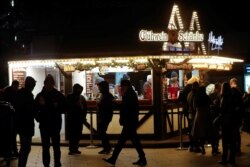 People stand around a mulled wine to-go stand at a Christmas market at Breitscheidplatz square, amid the COVID-19 pandemic in Berlin, Germany, Dec.10, 2020.