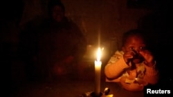 FILE: Thelelwa Simelane looks on as her daughter eats by candle light in Klipspruit, Soweto, South Africa, May 18, 2023. Power wires connect her house to the grid, but the source, state-owned utility Eskom, is highly unreliable with frequent outages. 