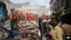 Seorang anggota Tim SAR memberikan pengumuman melalui pengeras suara di lokasi runtuhnya bangunan berlantai lima di Mumbai, India, Kamis, 31 Agustus 2017. (AP Photo/Rafiq Maqbool)