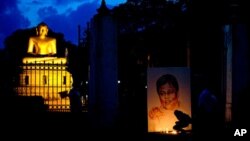 FILE - Family members and friends light candles next to a portrait of slain newspaper editor Lasantha Wickrematunge, on the fourth anniversary of his death, in Colombo, Sri Lanka, Jan. 8, 2013.