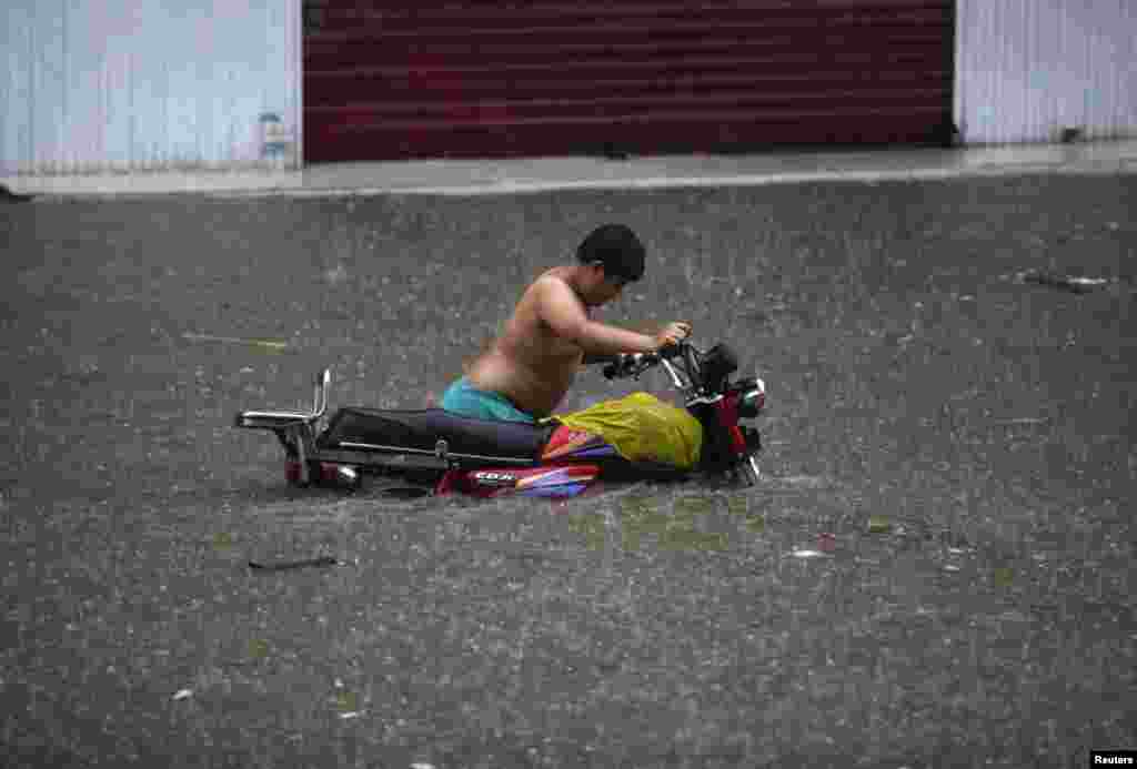 Seorang pengendara sepeda motor nekat menceburkan diri melewati jalanan yang banjir akibat hujan lebat di Lahore, Pakistan.