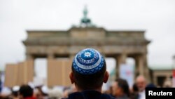 FILE - A man wearing a Jewish scullcap waits for the start of an anti-Semitism rally at Berlin's Brandenburg Gate, in Berlin, Germany Sept. 14, 2014.