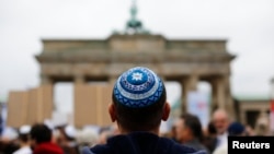 FILE - A man wearing a Jewish scullcap waits for the start of an anti-Semitism rally at Berlin's Brandenburg Gate, in Berlin, Germany Sept. 14, 2014.