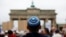 FILE - A man wearing a Jewish scullcap waits for the start of an anti-Semitism rally at Berlin's Brandenburg Gate, in Berlin, Germany Sept. 14, 2014.