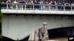 Quelques personnes regardent les eaux des inondations, se référant depuis le pont de l'Alma à la statue Zouave, repère généralement utilisé pour constater la montée des eaux à Paris, France 3 juin 2016. (AP Photo / Jerome Delay)