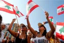 Demonstrators wave national flags during an anti-government protest in Beirut, Lebanon, Oct. 19, 2019.