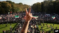 Seorang pria membuat gestur tangan yang merepresentasikan simbol kedamaian dalam aksi protes menentang rezim pemerintah Iran di Berlin, Jerman, 22 Oktober 2022. (Foto: AP/Markus Schreiber)