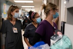 FILE - Nurses watch as medical workers try to resuscitate a COVID-19 patient in the emergency room at Providence Holy Cross Medical Center, in the Mission Hills section of Los Angeles, California, Nov. 19, 2020.