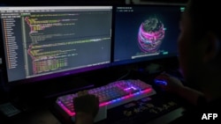 FILE: This photo taken on August 4, 2020 shows Prince, a member of the hacking group Red Hacker Alliance who refused to give his real name, using a website that monitors global cyberattacks on his computer at their office in Dongguan, China's southern Guangdong province.