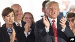 El presidente Donald Trump aplaude junto a los gobernadores Pete Ricketts, de Nebraska y Kim Reynolds, de Iowa, en Council Bluffs, Iowa, el 11 de junio de 2019. (AP Foto/Nati Harnik).