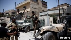 A member of Iraqi rapid response forces jumps out of a vehicle during clashes with Islamic State fighters in western Mosul, Iraq, May 27, 2017. 