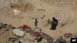 A woman and her children, who left the besieged Islamic State-held village of Baghuz, Syria, scramble over a rocky hillside to be checked by U.S-backed Syrian Democratic Forces, March 14, 2019.