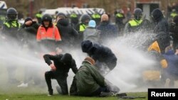 Polisi menggunakan meriam air untuk membubarkan unjuk rasa menentang pembatasan aktivitas untuk meredam penyebaran virus corona di Amsterdam, Belanda, Minggu, 24 Januari 2021. 