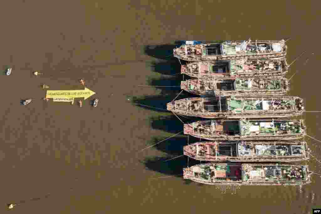 In this handout picture released by Greenpeace, activists of the non-governmental environmental organization display a 25-meter-long arrow that reads ‘Looters of the Oceans,’ pointing to South Korea&#39;s fishing vessels at the port of Montevideo, Uruguay.