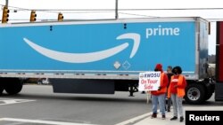 Varias personas levantan un cartel en una instalación de Amazon mientras miembros de una delegación del Congreso llegan para expresar su apoyo a trabajadores que buscan sindicalizarse en Bessemer, Alabama.