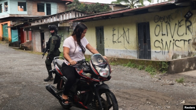 Una mujer conduce su motocicleta cerca de una casa que exhibe grafitis del Ejército de Liberación Nacional (ELN) y del frente Oliver Sineterra de disidentes de las Fuerzas Armadas Revolucionarias de Colombia (FARC) en Tumaco, Colombia, 9 de septiembre de 2022. REUTERS/Luisa González