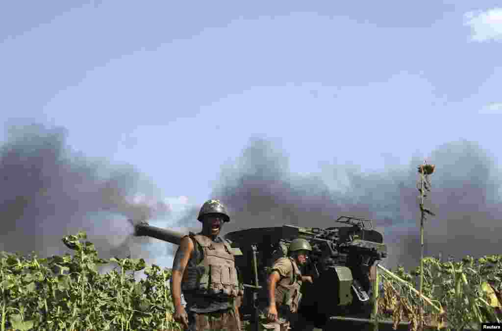 Ukrainian servicemen, who are members of an artillery section, gather near a cannon being fired during a military operation against pro-Russian separatists near Pervomaisk, Luhansk region, Aug. 2, 2014.