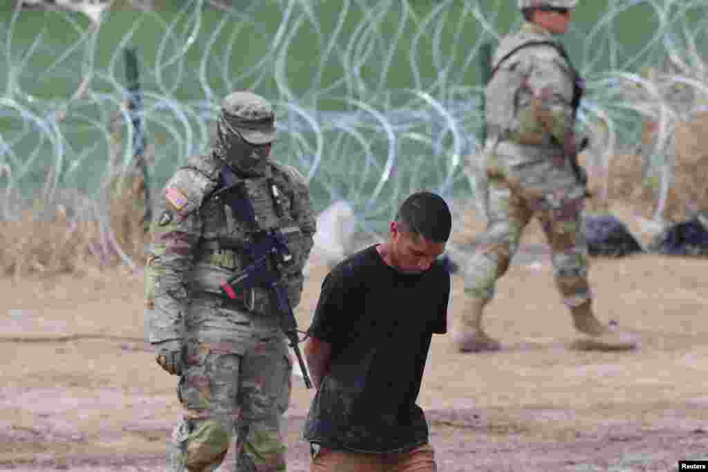 A migrant is detained in handcuffs by authorities after crossing the Rio Grande into the United States in Eagle Pass, Texas, Sept. 26, 2023.&nbsp;