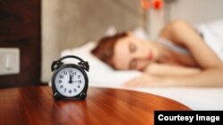 Woman asleep with an alarm clock.