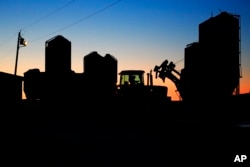 A worker drives a tractor to the feed silos at the Flood Brothers Farm, Monday, April 1, 2024, in Clinton, Maine. Foreign-born workers make up fully half the farm's staff of nearly 50. (AP Photo/Robert F. Bukaty)