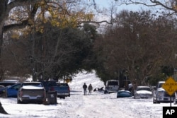 People walk from the snow-covered Mississippi River levee the day after a rare and record-setting snowstorm in Harahan, Louisiana, Jan. 22, 2025. (AP Photo/Gerald Herbert)