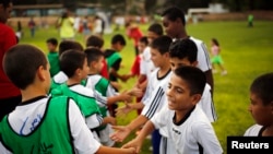 Anak-anak Israel dan Palestina saling bersalaman sebelum pembukaan program pelatihan sepakbola kedua negara yang diluncurkan oleh Peres Center for Peace, di Kibbutz Dorot, di luar Jalur Gaza, 2014. (Reuters/Amir Cohen)