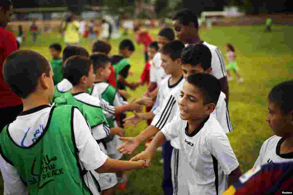 Israeli and Palestinian children shake hands during an event opening a year of training in an Israeli-Palestinian soccer program launched by the Peres Center for Peace, in Kibbutz Dorot, outside the Gaza Strip, Sept. 1, 2014.