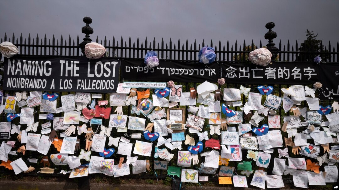 FILE - A fence outside Brooklyn's Green-Wood Cemetery is adorned with tributes to victims of COVID-19, in New York City, May 28, 2020.
