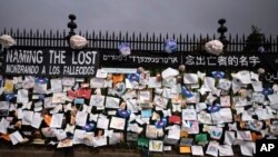 FILE - A fence outside Brooklyn's Green-Wood Cemetery is adorned with tributes to victims of COVID-19, in New York City, May 28, 2020.